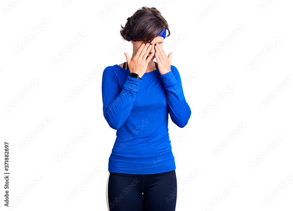 Beautiful young woman with short hair wearing training workout clothes rubbing eyes for fatigue and headache, sleepy and tired expression. vision problem Beautiful young woman with short hair wearing training workout clothes rubbing eyes for fatigue and headache, sleepy and tired expression. vision problem