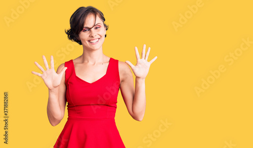 Beautiful young woman with short hair wearing casual style with sleeveless shirt showing and pointing up with fingers number ten while smiling confident and happy.