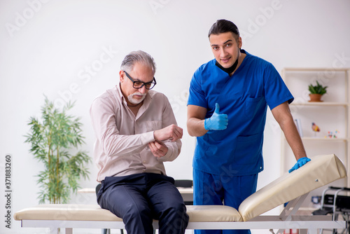 Old patient visiting young male doctor in blood sampling concept