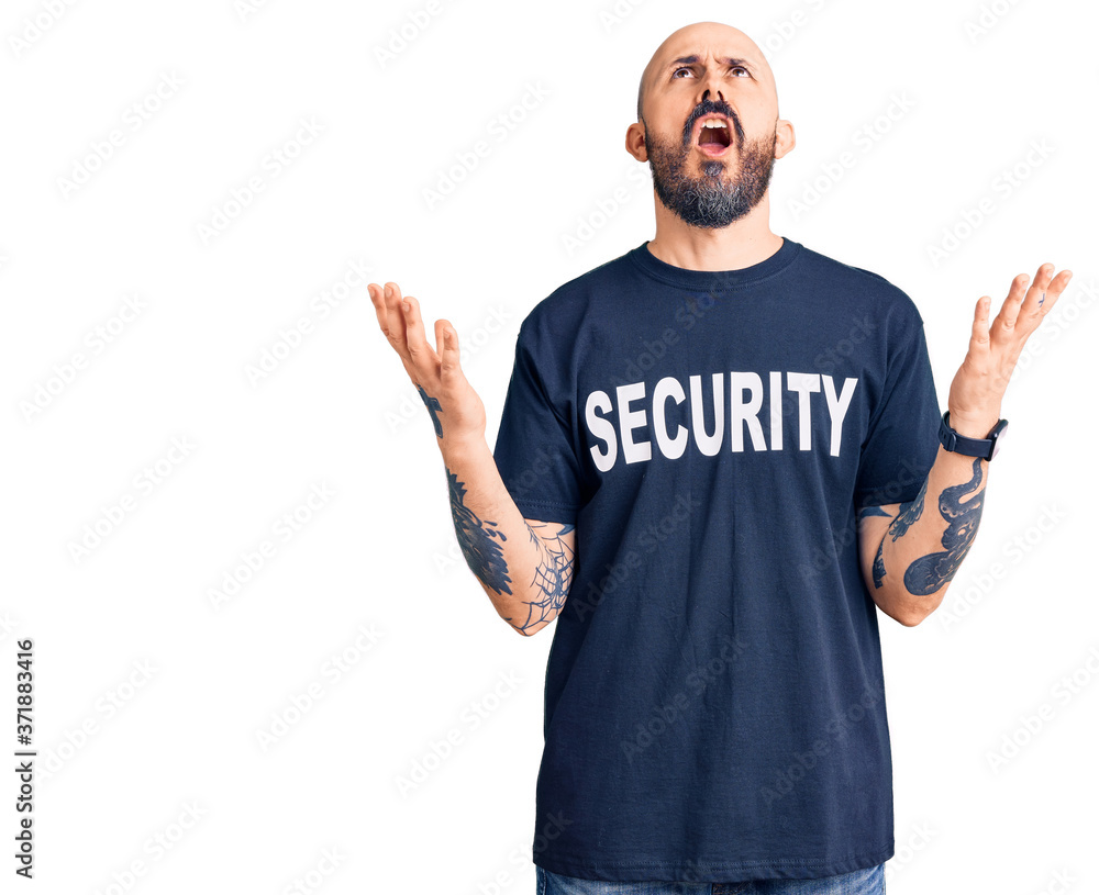 Fototapeta premium Young handsome man wearing security t shirt crazy and mad shouting and yelling with aggressive expression and arms raised. frustration concept.