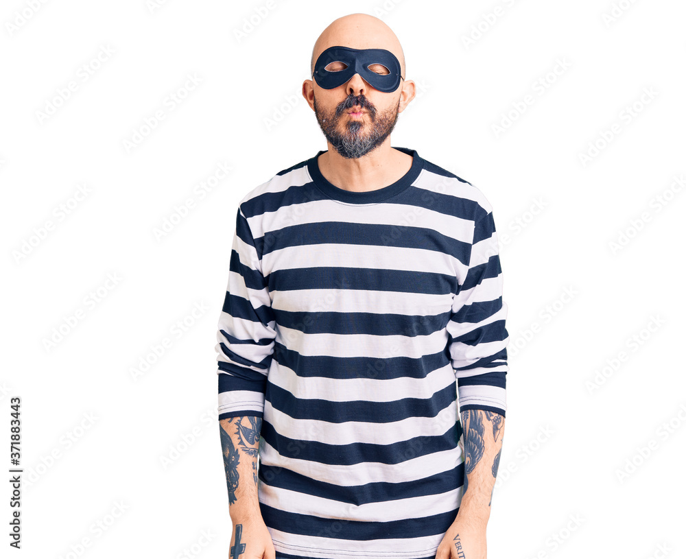 Young handsome man wearing burglar mask looking at the camera blowing a kiss on air being lovely and sexy. love expression. Young handsome man wearing burglar mask looking at the camera blowing a kiss on air being lovely and sexy. love expression.