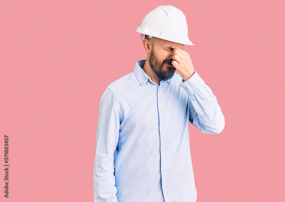 Young handsome man wearing architect hardhat tired rubbing nose and eyes feeling fatigue and headache. stress and frustration concept.