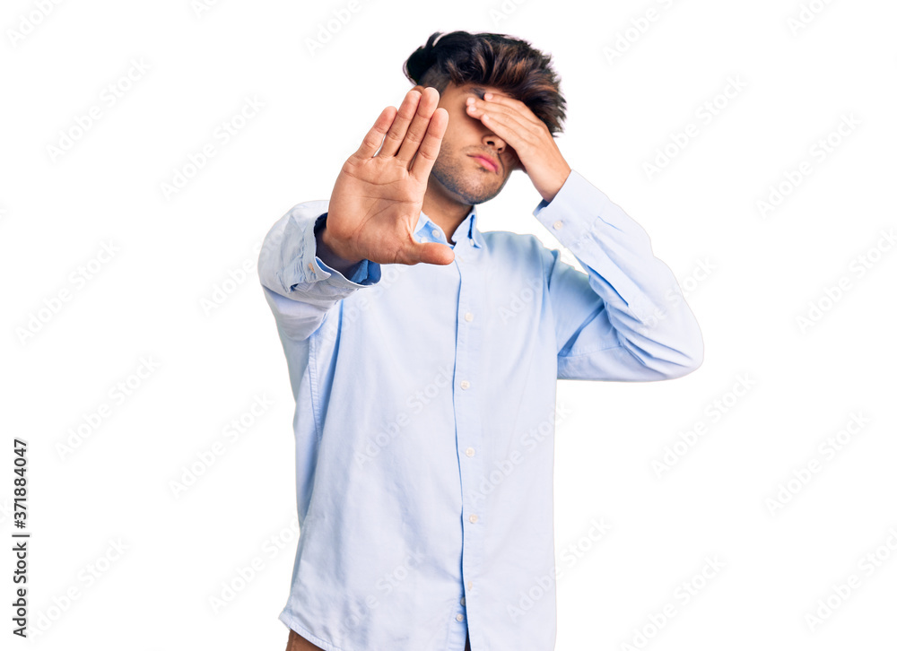 Young hispanic man wearing casual shirt covering eyes with hands and doing stop gesture with sad and fear expression. embarrassed and negative concept.