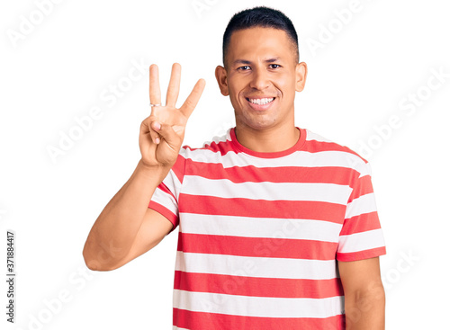 Young handsome latin man wearing casual clothes showing and pointing up with fingers number three while smiling confident and happy.
