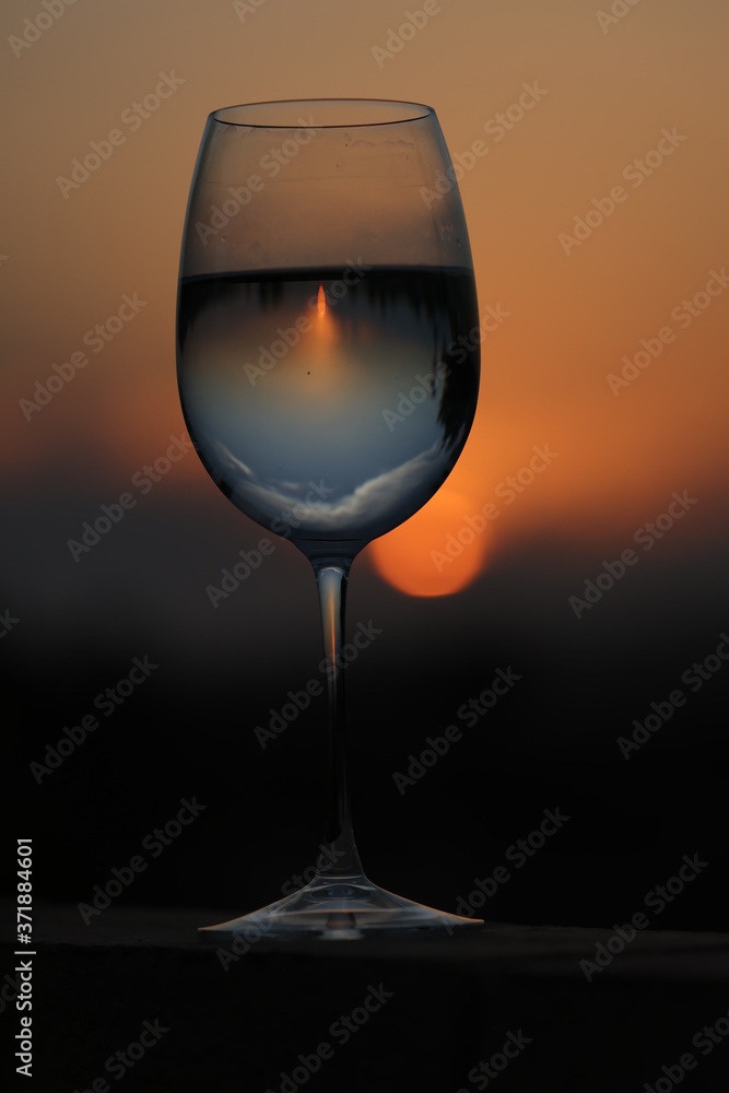Reflection of the sun at sunset through a glass of wine.