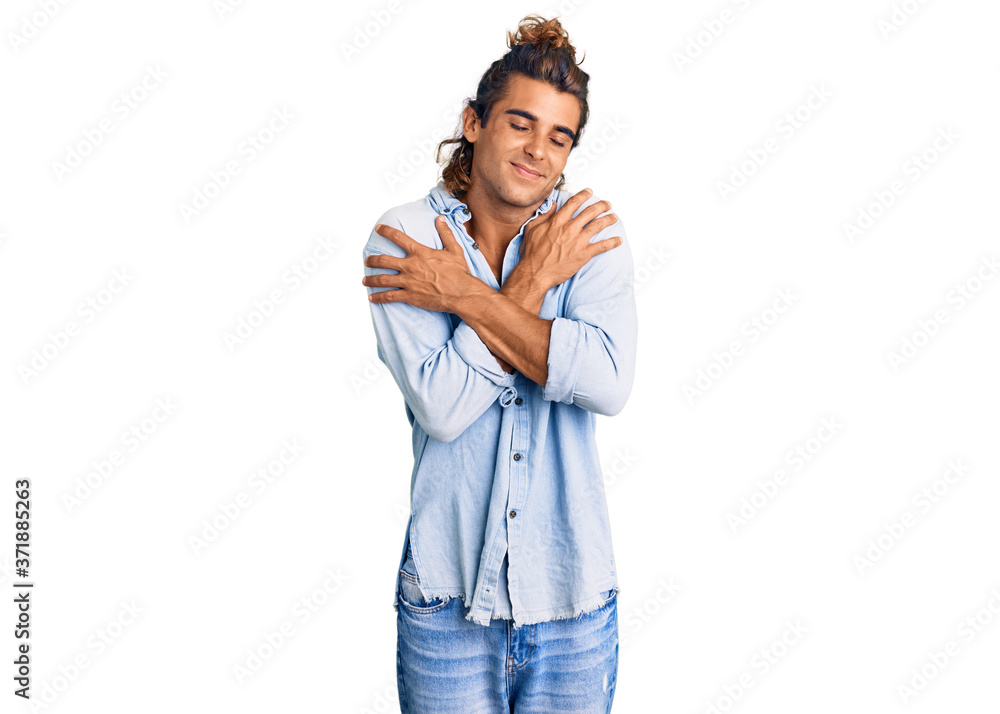 Young hispanic man wearing summer style hugging oneself happy and positive, smiling confident. self love and self care Young hispanic man wearing summer style hugging oneself happy and positive, smiling confident. self love and self care