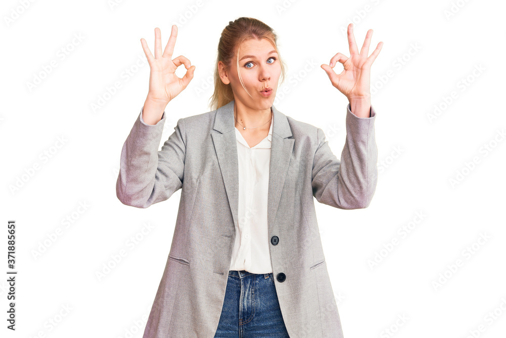 Young beautiful blonde woman wearing elegant jacket looking surprised and shocked doing ok approval symbol with fingers. crazy expression Young beautiful blonde woman wearing elegant jacket looking surprised and shocked doing ok approval symbol with fingers. crazy expression