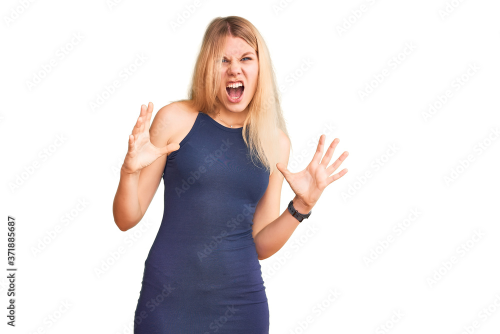 Young beautiful blonde woman wearing casual dress crazy and mad shouting and yelling with aggressive expression and arms raised. frustration concept.