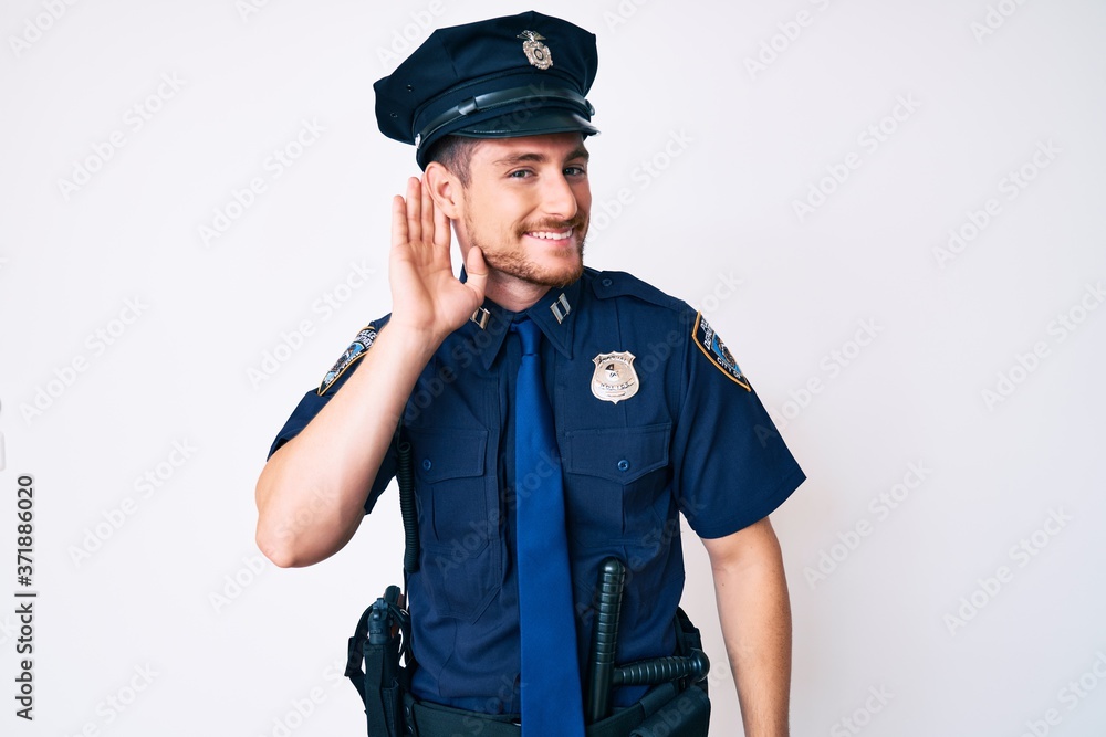 Young caucasian man wearing police uniform smiling with hand over ear listening an hearing to rumor or gossip. deafness concept. Young caucasian man wearing police uniform smiling with hand over ear listening an hearing to rumor or gossip. deafness concept.