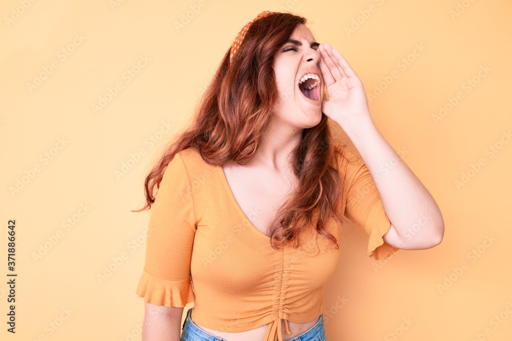 Young beautiful woman wearing casual clothes shouting and screaming loud to side with hand on mouth. communication concept. Young beautiful woman wearing casual clothes shouting and screaming loud to side with hand on mouth. communication concept.