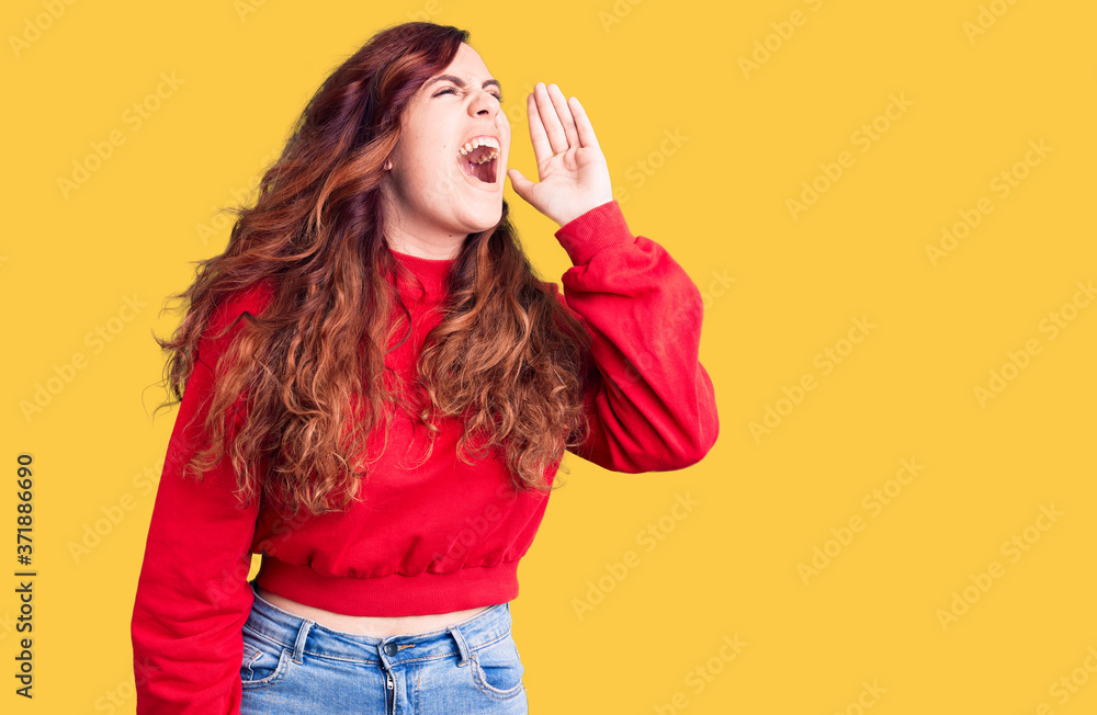 Young beautiful woman wearing casual winter sweater shouting and screaming loud to side with hand on mouth. communication concept. Young beautiful woman wearing casual winter sweater shouting and screaming loud to side with hand on mouth. communication concept.