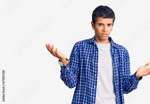 Young african amercian man wearing casual clothes clueless and confused with open arms, no idea concept.