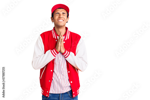 Young african amercian man wearing baseball uniform begging and praying with hands together with hope expression on face very emotional and worried. begging.