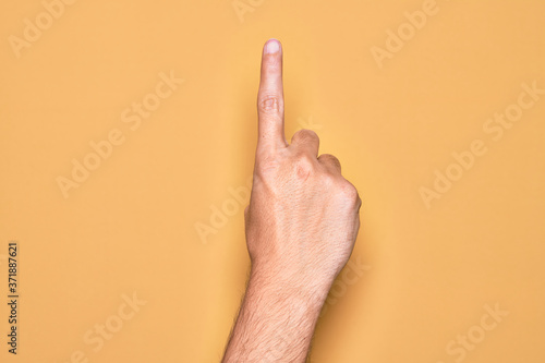 Photos Hand of caucasian young man showing fingers over isolated yellow background coun