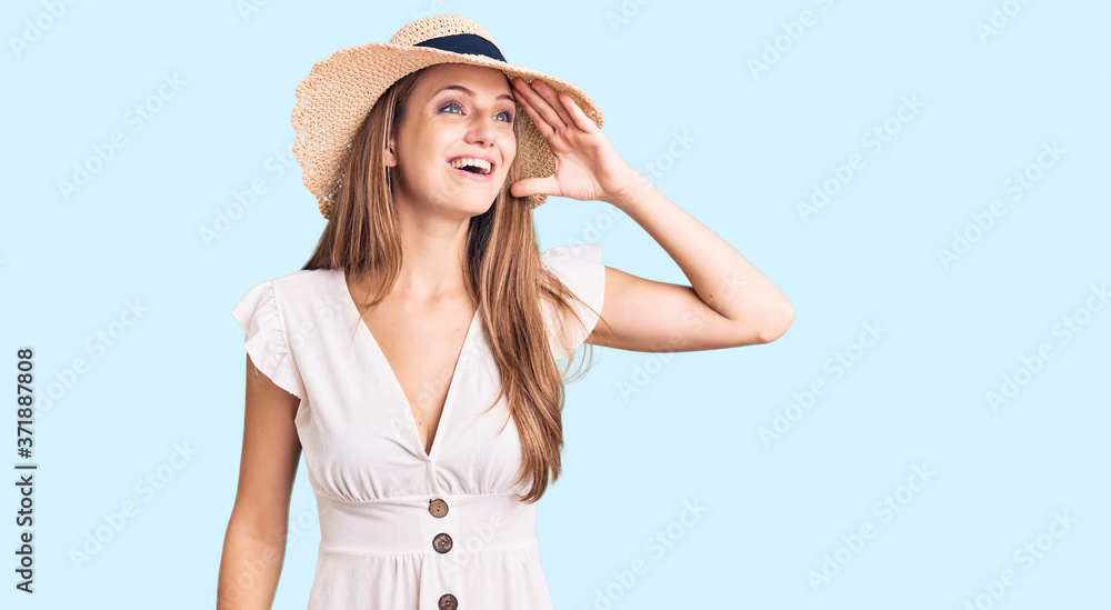 Young beautiful blonde woman wearing summer dress and hat very happy and smiling looking far away with hand over head. searching concept. Young beautiful blonde woman wearing summer dress and hat very happy and smiling looking far away with hand over head. searching concept.