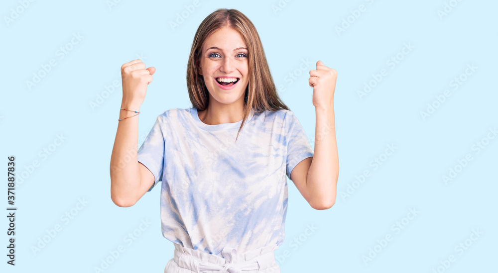 Young beautiful blonde woman wearing tye die tshirt screaming proud, celebrating victory and success very excited with raised arms Young beautiful blonde woman wearing tye die tshirt screaming proud, celebrating victory and success very excited with raised arms