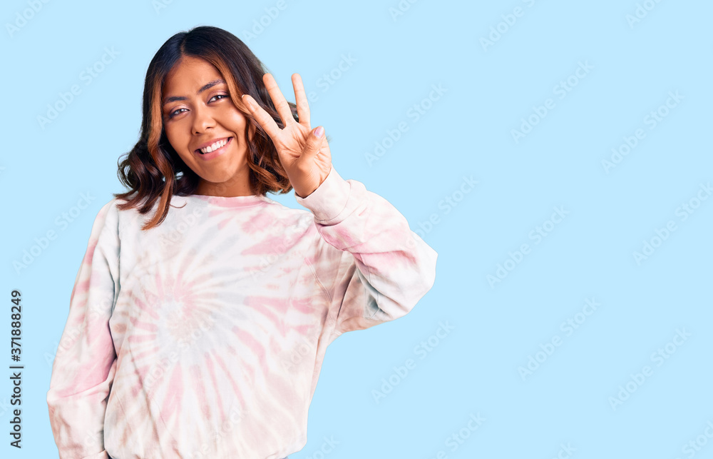 Young beautiful mixed race woman wearing casual tie dye sweatshirt showing and pointing up with fingers number three while smiling confident and happy. Young beautiful mixed race woman wearing casual tie dye sweatshirt showing and pointing up with fingers number three while smiling confident and happy.