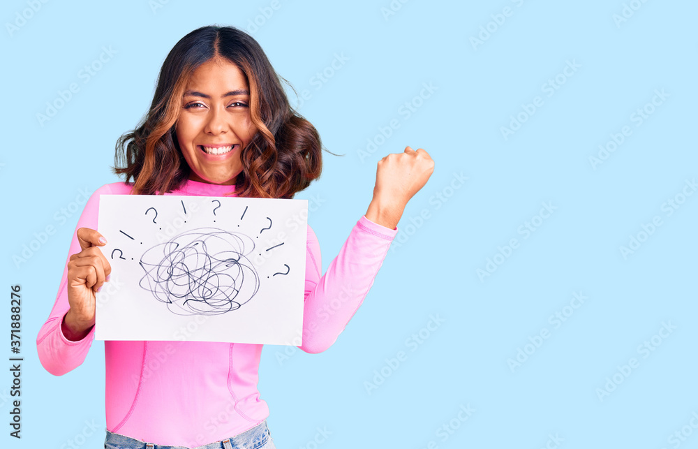 Young beautiful mixed race woman holding scribble draw screaming proud, celebrating victory and success very excited with raised arms Young beautiful mixed race woman holding scribble draw screaming proud, celebrating victory and success very excited with raised arms