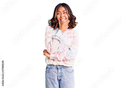 Young beautiful mixed race woman wearing casual tie dye sweatshirt looking confident at the camera smiling with crossed arms and hand raised on chin. thinking positive.