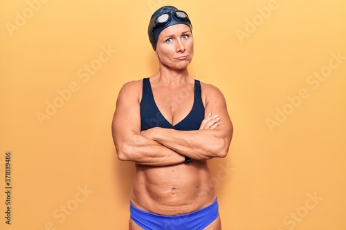 Middle age caucasian blonde woman wearing bikini,  swimming cap and diving googles skeptic and nervous, disapproving expression on face with crossed arms. negative person. © Krakenimages.com