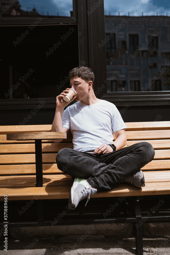 Brunette man in street cafe drinks coffee. Brunette man in street cafe drinks coffee.