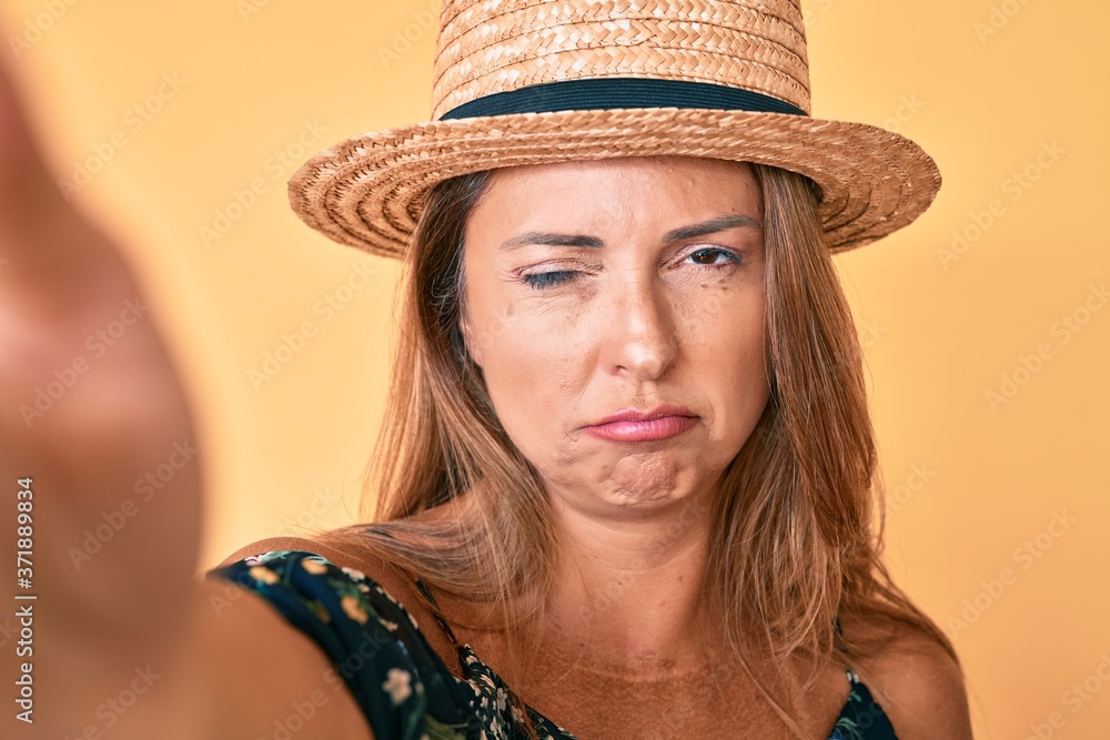 Middle age hispanic woman wearing summer hat taking a selfie skeptic and nervous, frowning upset because of problem. negative person. Middle age hispanic woman wearing summer hat taking a selfie skeptic and nervous, frowning upset because of problem. negative person.