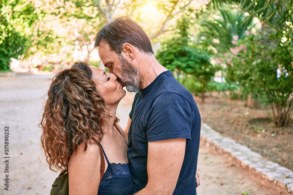 Fototapeta premium Middle age couple wearing casual clothes kissing at the forest
