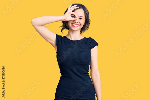 Young beautiful girl wearing casual clothes smiling happy doing ok sign with hand on eye looking through fingers