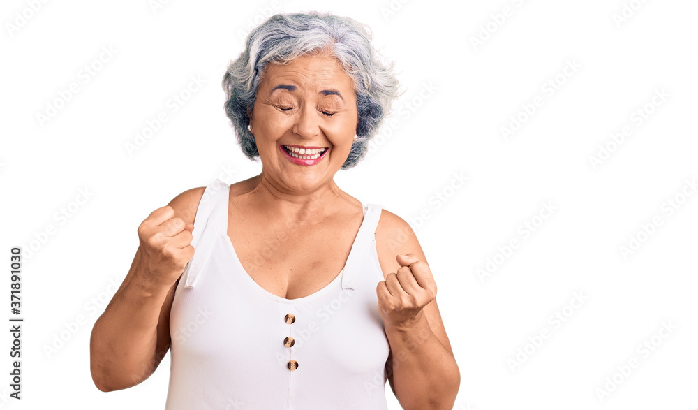 Senior woman with gray hair wearing casual clothes very happy and excited doing winner gesture with arms raised, smiling and screaming for success. celebration concept. Senior woman with gray hair wearing casual clothes very happy and excited doing winner gesture with arms raised, smiling and screaming for success. celebration concept.