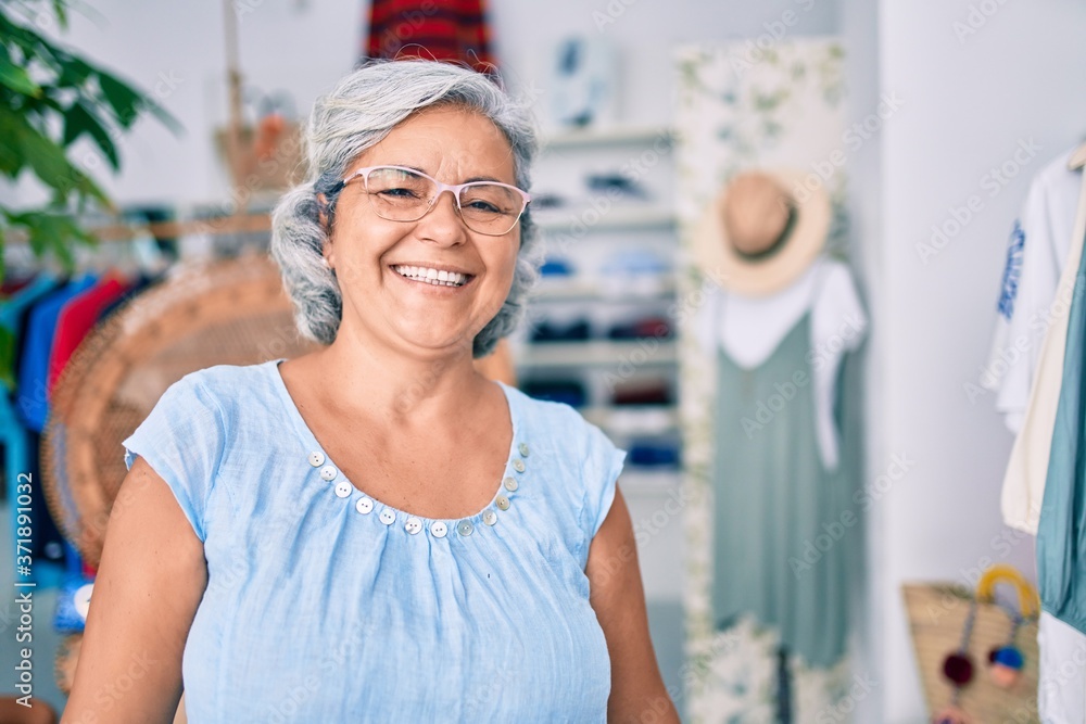 Middle age woman with grey hair at retail shop smiling happy