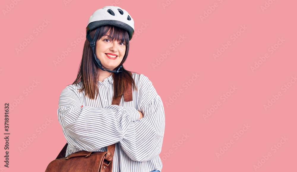 Young plus size woman wearing bike helmet and leather bag happy face smiling with crossed arms looking at the camera. positive person. Young plus size woman wearing bike helmet and leather bag happy face smiling with crossed arms looking at the camera. positive person.