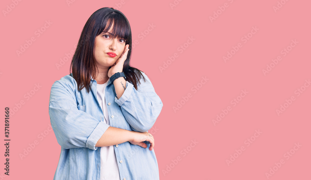 Young plus size woman wearing casual clothes thinking looking tired and bored with depression problems with crossed arms. Young plus size woman wearing casual clothes thinking looking tired and bored with depression problems with crossed arms.