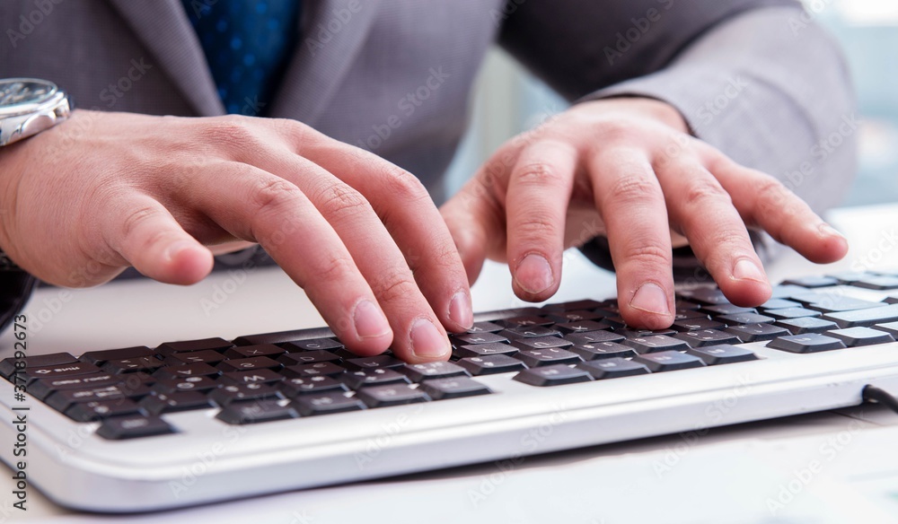 Finance professional working on keyboard with reports Finance professional working on keyboard with reports