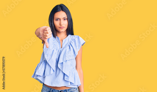 Young beautiful latin girl wearing casual clothes looking unhappy and angry showing rejection and negative with thumbs down gesture. bad expression. © Krakenimages.com
