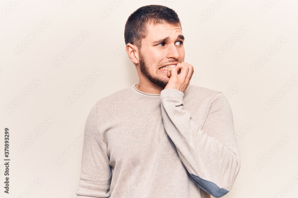 Young handsome man wearing casual sweater looking stressed and nervous with hands on mouth biting nails. anxiety problem. Young handsome man wearing casual sweater looking stressed and nervous with hands on mouth biting nails. anxiety problem.