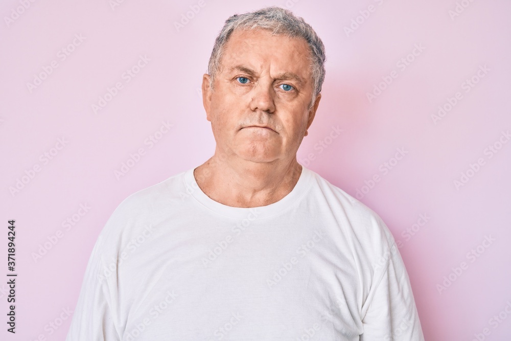 Senior grey-haired man wearing casual white tshirt with serious expression on face. simple and natural looking at the camera. Senior grey-haired man wearing casual white tshirt with serious expression on face. simple and natural looking at the camera.