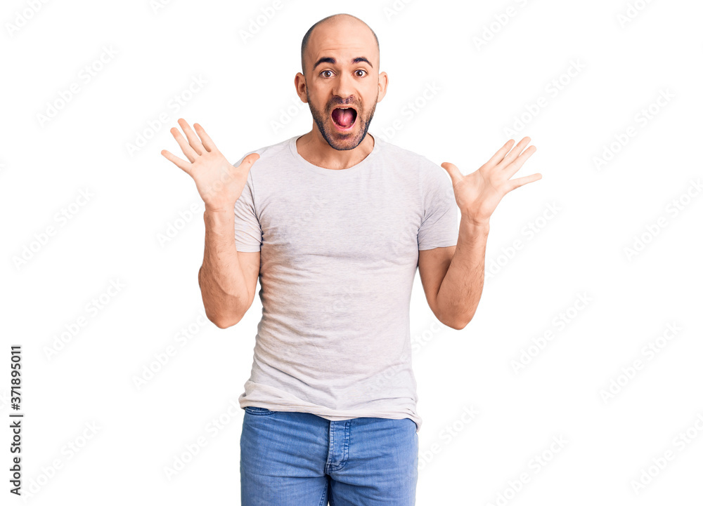 Fototapeta premium Young handsome man wearing casual t shirt celebrating crazy and amazed for success with arms raised and open eyes screaming excited. winner concept