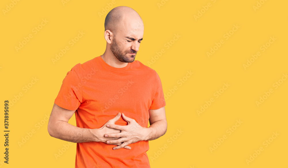 Young handsome man wering casual t shirt with hand on stomach because indigestion, painful illness feeling unwell. ache concept. Young handsome man wering casual t shirt with hand on stomach because indigestion, painful illness feeling unwell. ache concept.