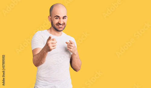 Young handsome man wearing casual t shirt pointing fingers to camera with happy and funny face. good energy and vibes.