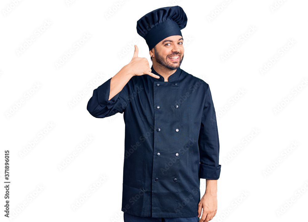 Young hispanic man wearing cooker uniform smiling doing phone gesture with hand and fingers like talking on the telephone. communicating concepts. Young hispanic man wearing cooker uniform smiling doing phone gesture with hand and fingers like talking on the telephone. communicating concepts.