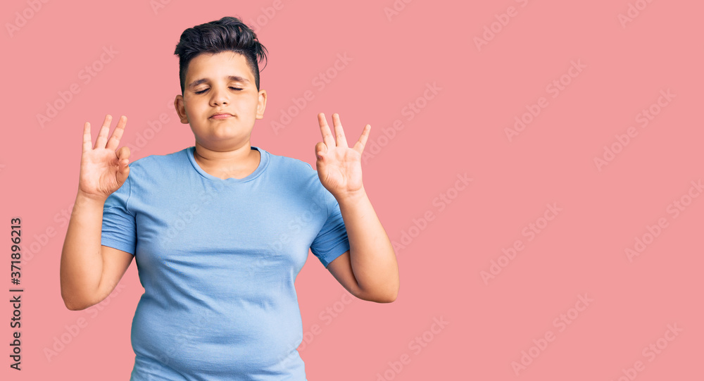 Little boy kid wearing sports workout clothes relax and smiling with eyes closed doing meditation gesture with fingers. yoga concept. Little boy kid wearing sports workout clothes relax and smiling with eyes closed doing meditation gesture with fingers. yoga concept.