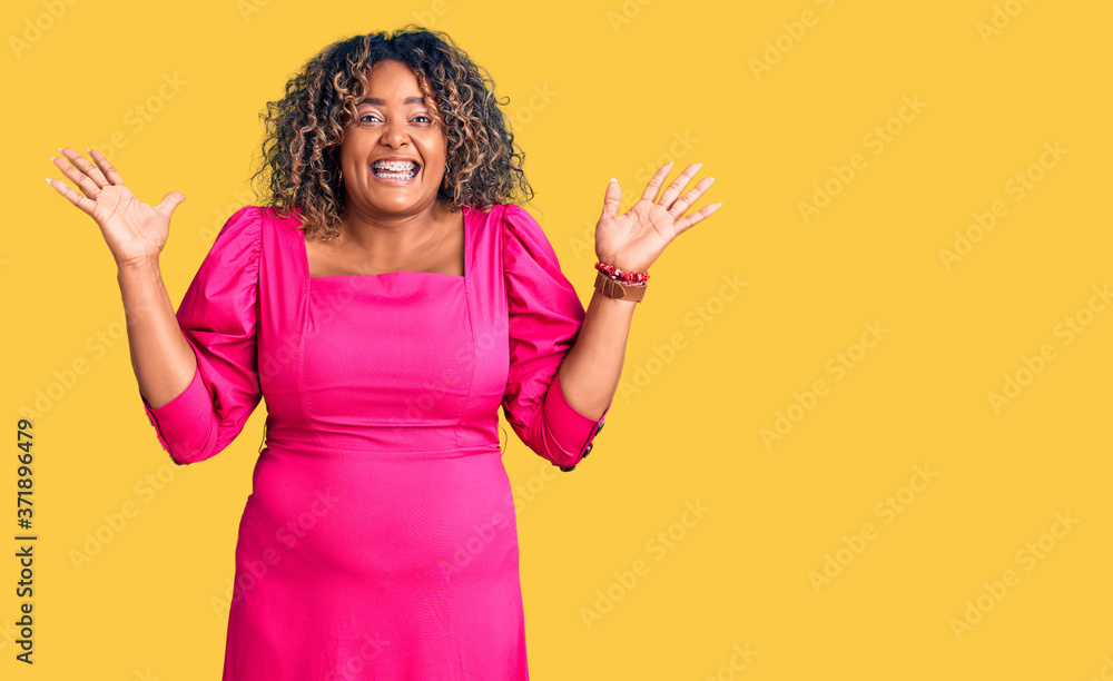 Young african american plus size woman wearing casual clothes celebrating victory with happy smile and winner expression with raised hands Young african american plus size woman wearing casual clothes celebrating victory with happy smile and winner expression with raised hands