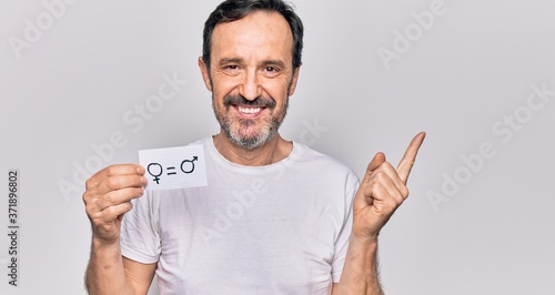 Middle age man asking for rights holding paper with equality male and female concept smiling happy pointing with hand and finger to the side