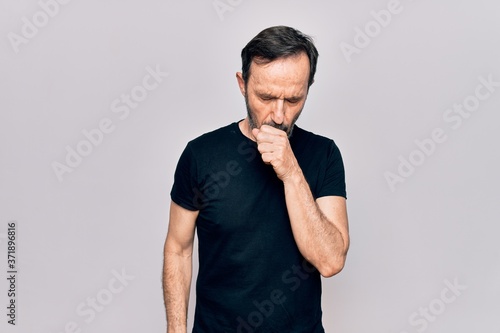 Middle age man wearing casual black t-shirt standing over isolated white background feeling unwell and coughing as symptom for cold or bronchitis. Health care concept.
