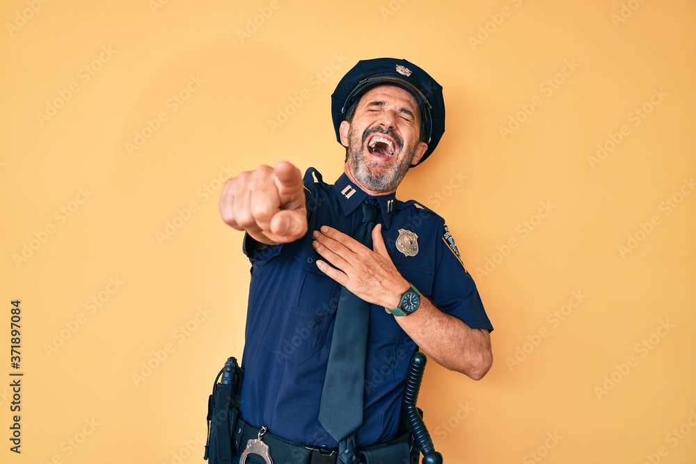 Middle age hispanic man wearing police uniform laughing at you, pointing finger to the camera with hand over body, shame expression Middle age hispanic man wearing police uniform laughing at you, pointing finger to the camera with hand over body, shame expression