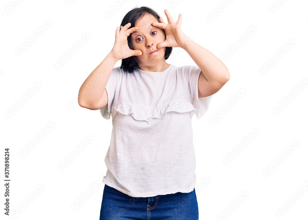 Brunette woman with down syndrome wearing casual white tshirt trying to open eyes with fingers, sleepy and tired for morning fatigue Brunette woman with down syndrome wearing casual white tshirt trying to open eyes with fingers, sleepy and tired for morning fatigue