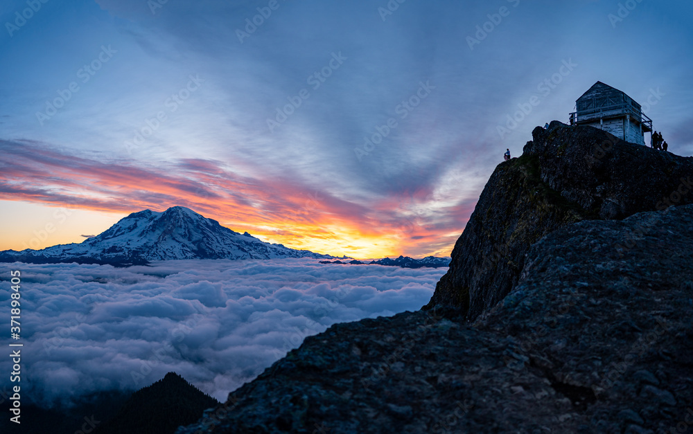 Panoramic view of Mount Rainier above the clouds during the sunrise with dramatic color in the sky