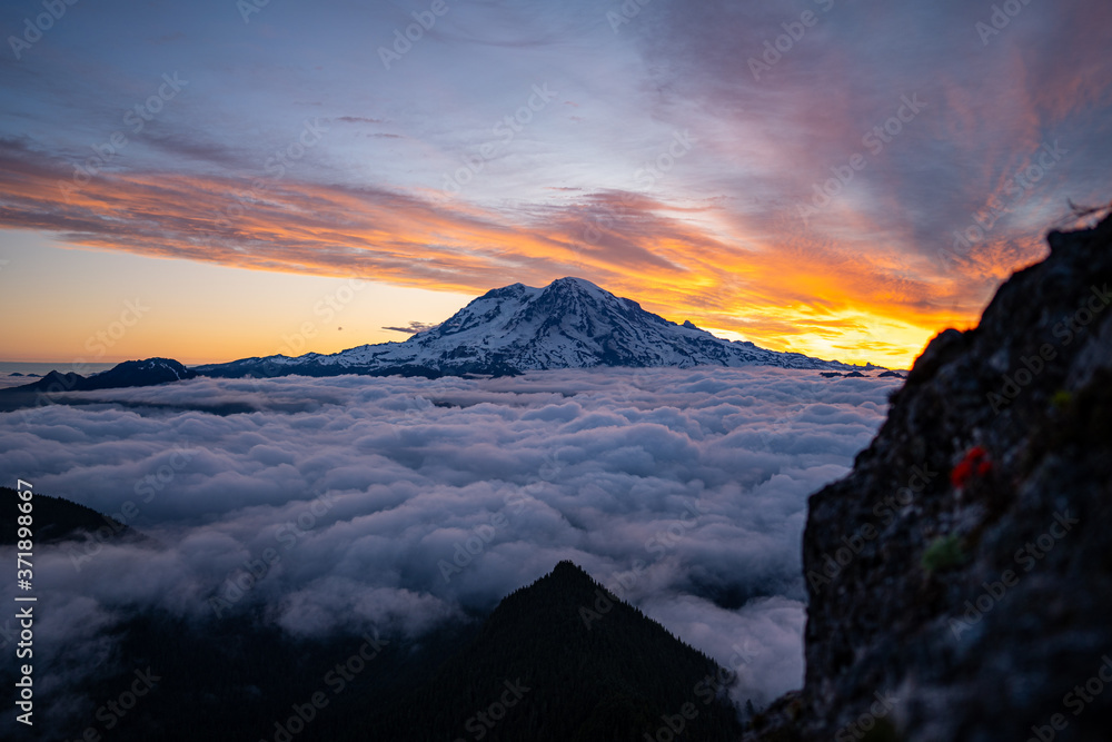 Obraz premium Panoramic view of Mount Rainier above the clouds during the sunrise with dramatic color in the sky