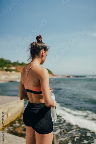 Fototapeta Naklejka Na Ścianę i Meble -  Woman drinking fresh water from bottle after exercise on beach