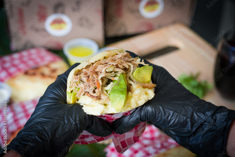 person with arepa in hands, person eating arepas, person showing arepa